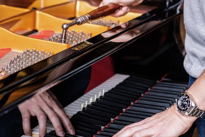 man tuning a Yamaha piano