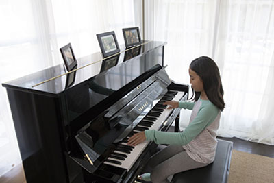 Woman playing a Yamaha U1 upright piano